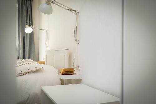 a white bedroom with a bed and a table at Depto in Sassari