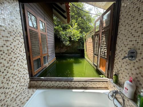 a bath tub with a window and a pool of water at Fresia Villa & Camping in Beranang