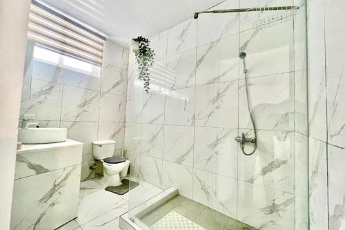 Un baño blanco con ducha y WC. en Grecialandia, en San Felipe de Puerto Plata