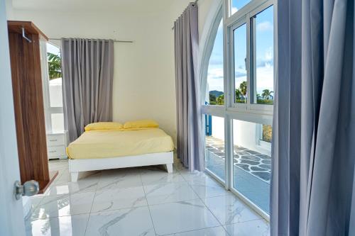 Un dormitorio con una cama y una ventana grande. en Grecialandia, en San Felipe de Puerto Plata