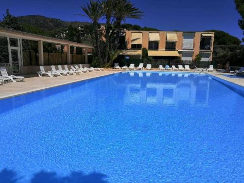 une grande piscine bleue avec des chaises et un bâtiment dans l'établissement Appartement avec superbe terrasse pour 4 personnes, au Lavandou