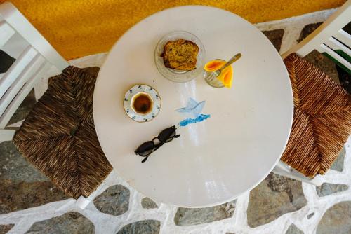 a white table with a plate of food and sunglasses on it at Vagia Traditional, Aegina Island in Vaia