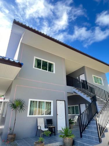 a white house with a staircase and some plants at Boonyawat Apartment in Kata Beach
