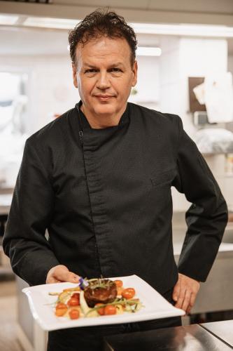 a man holding a plate of food in a kitchen at Wohlfühlhotel Innertalerhof in Gerlos