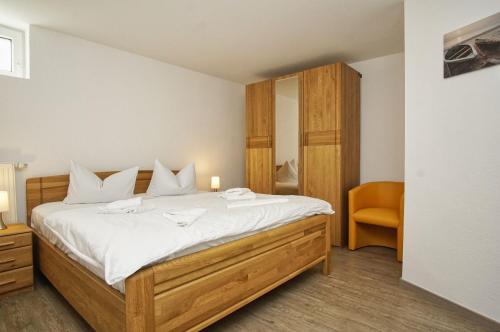 une chambre avec un grand lit et une chaise dans l'établissement FeWo am Hochzeitsberg FeWo 17 - Souterrain, à Breege