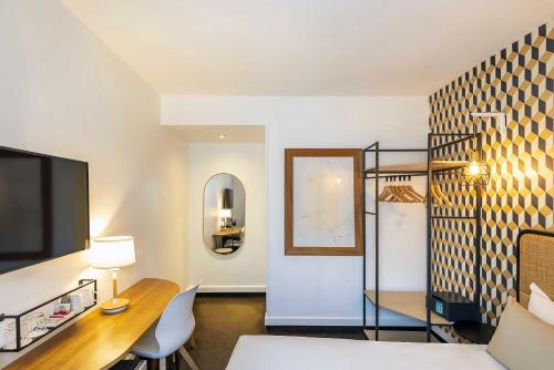 a room with a bed and a desk and a mirror at Best Western Aramis Saint Germain in Paris