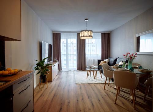 a kitchen and living room with a table and a dining room at Luxusowy Apartament Staszica in Koszalin