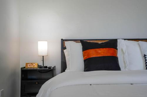 a white bed with a black and orange pillow on it at The Jaxon in West Palm Beach