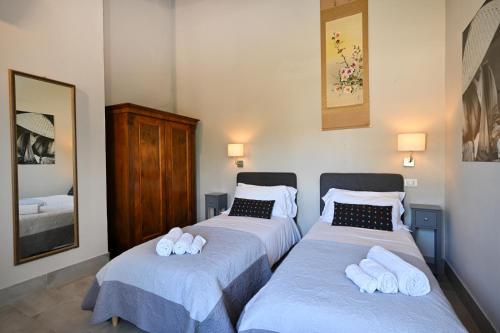 a bedroom with two beds with towels on them at La Grande Via, ospitalità in Maremma in Montemerano