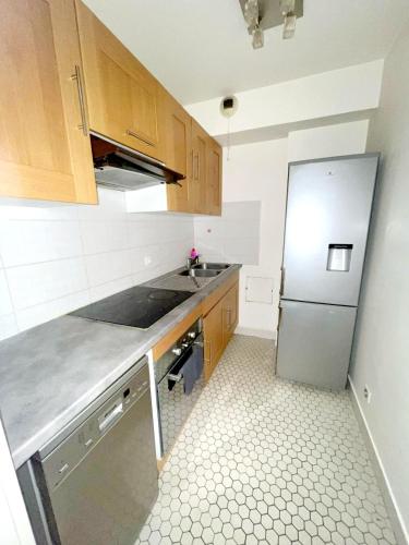 une cuisine avec des armoires en bois et un réfrigérateur en acier inoxydable dans l'établissement Floor sixteen, à Puteaux