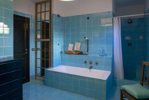 een blauwe betegelde badkamer met een bad en een douche bij Villa Il Bagno in Bagno