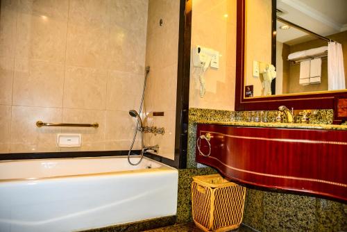 a bathroom with a tub and a sink and a mirror at Regal Palace Hotel in Dongguan