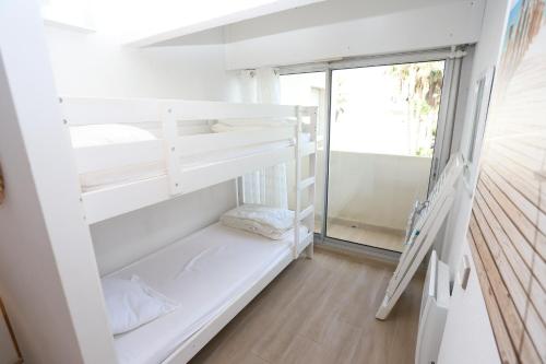 Cette chambre dispose d'étagères blanches et d'une fenêtre. dans l'établissement Appart vue mer accès plage et piscine à 30m, à Saint-Cyprien