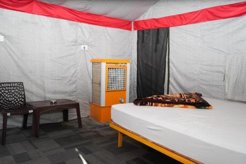 a bed in a tent with a chair and a table at Rudra Adventures in Rishīkesh