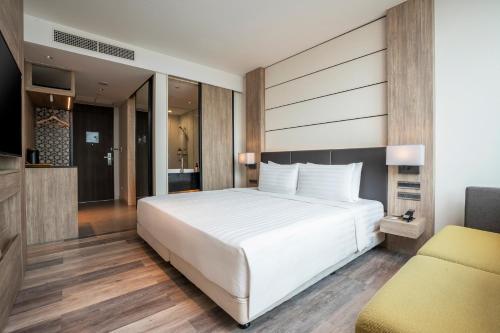 a bedroom with a large white bed and a couch at Solaria Nishitetsu Hotel Bangkok in Bangkok