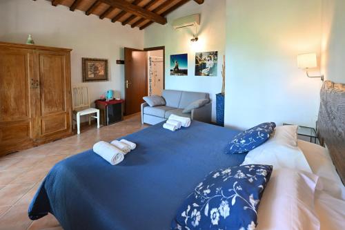 a bedroom with a blue bed with towels on it at La Grande Via, ospitalità in Maremma in Montemerano