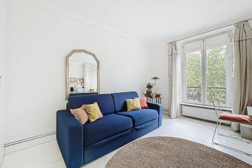 un canapé bleu dans un salon avec un miroir dans l'établissement Spacious apartment near Bastille & le Marais, à Paris