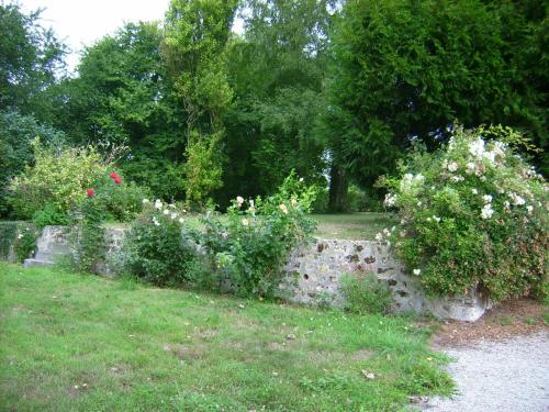 un mur en pierre avec des fleurs dans un jardin dans l'établissement Chambre d'hôte au domaine de la Miottiere, à Le Pin-la-Garenne