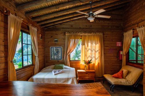 a bedroom in a log cabin with a bed and a window at Las Cabañas Encantadas de Nindirí in Nindirí