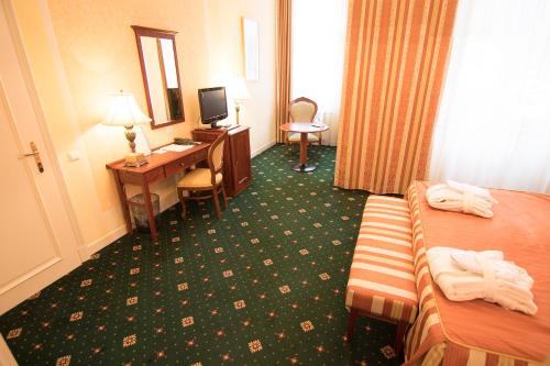 a hotel room with a bed and a desk with a computer at Humboldt Park Hotel & Spa in Karlovy Vary
