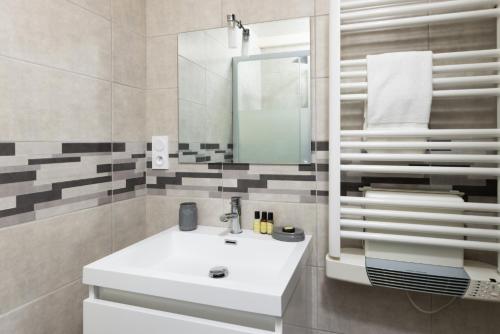 une salle de bain avec un lavabo blanc et un miroir dans l'établissement L'atelier De La Cite - Parking Gratuit Sécurisé, à Carcassonne