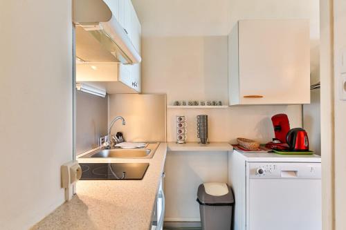 une petite cuisine avec des armoires blanches et un évier dans l'établissement Marina - Joli studio face à l'océan, à Saint-Jean-de-Monts