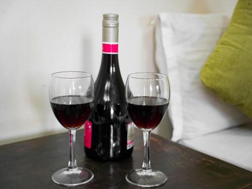 two glasses of red wine next to a bottle of wine at Naya Gaun Eco Resort in Pokhara