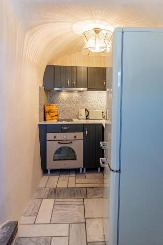 a small kitchen with a stove and a refrigerator at Parastia Luxury Villa Santorini - Private Jacuzzi in Éxo Goniá