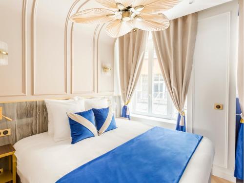 - une chambre avec un lit bleu et blanc et un ventilateur de plafond dans l'établissement Merveil - Luxury Suite - Louvre - Palestro, à Paris