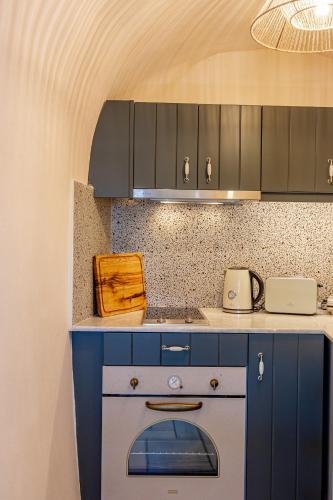 a kitchen with blue cabinets and a stove at Parastia Luxury Villa Santorini - Private Jacuzzi in Éxo Goniá