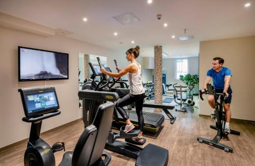 a man and woman exercising on exercise bikes in a gym at Best Western Plus Hotel Erb in Parsdorf