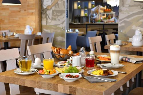 a wooden table topped with breakfast foods and drinks at Best Western Plus Hotel Erb in Parsdorf