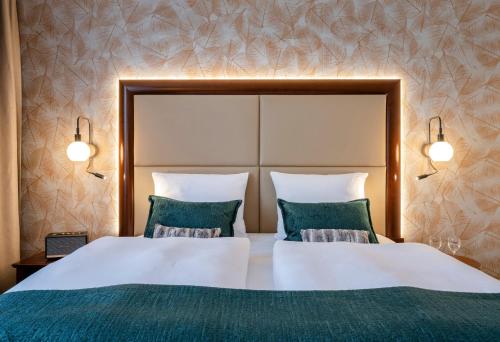 a bedroom with two beds with green pillows at Best Western Plus Hotel Erb in Parsdorf