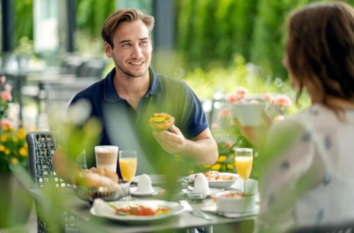 a man eating food at a table with a woman at Best Western Plus Hotel Erb in Parsdorf