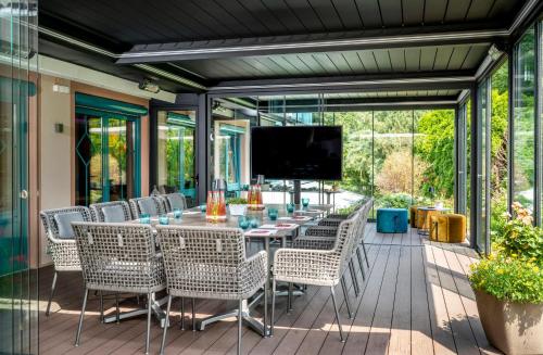 a screened patio with a table and chairs and a television at Best Western Plus Hotel Erb in Parsdorf