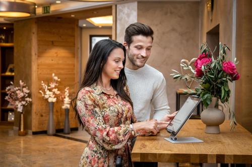 a man and a woman standing at a table with a laptop at Best Western Plus Hotel Erb in Parsdorf