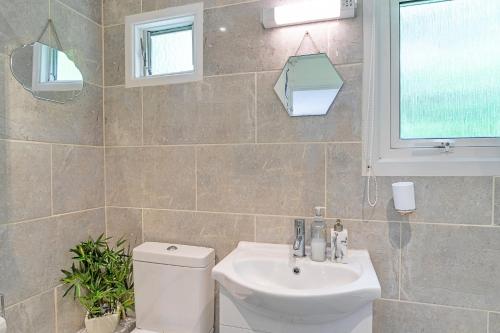 un bagno con un water, un lavandino e una finestra di Finest Retreats - Lanteglos Villa a Camelford