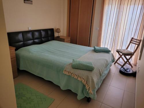 a bedroom with a bed with a black headboard and a chair at A Cabaninha - T2 Cabanas Beach in Tavira