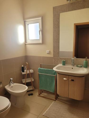 a bathroom with a sink and a toilet and a mirror at A Cabaninha - T2 Cabanas Beach in Tavira