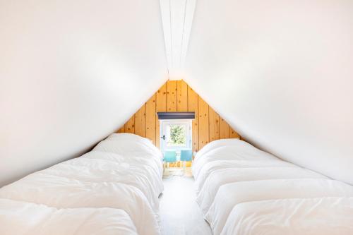 - une rangée de lits blancs dans une chambre dans l'établissement Mobilhome et chalet Guilvinec, au Guilvinec