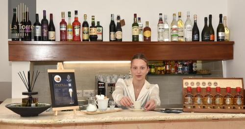 a woman standing behind a counter at a bar at La Torre Hotel in Moie