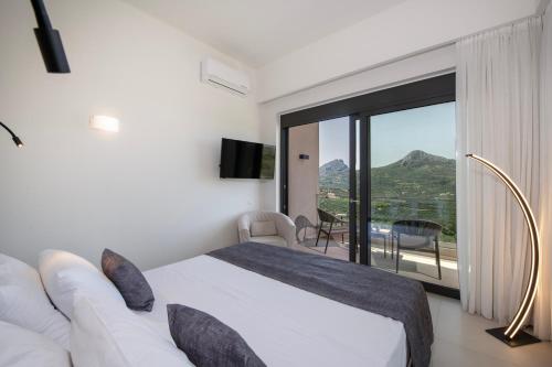 a bedroom with a bed and a balcony with a view at Porti Villas Aphrodite in Asómatoi