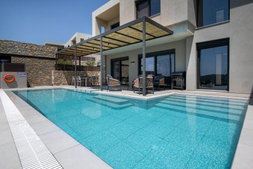 a swimming pool in front of a house at Porti Villas Aphrodite in Asómatoi