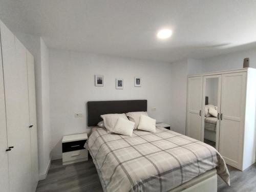a white bedroom with a bed with two pillows at Casa Nentis in Mucientes