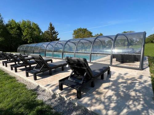 a row of chairs sitting in front of a glass house at La Millière - Piscine & Campagne - D'Elbée in Le Poiré-sur-Vie