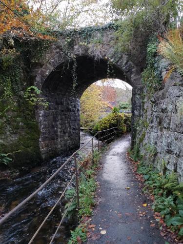 an old stone bridge over a river with a path at the Nook, Romantic cottage for two, Dartmoor and SW coast in Bovey Tracey