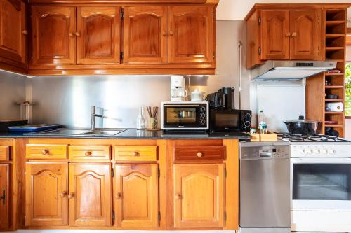 a kitchen with wooden cabinets and a microwave at Gîte Dalina in Saint-François
