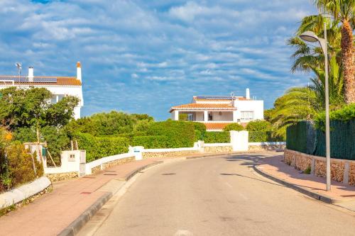 a road in front of a white house with palm trees at Casa del Ram in Cala en Blanes