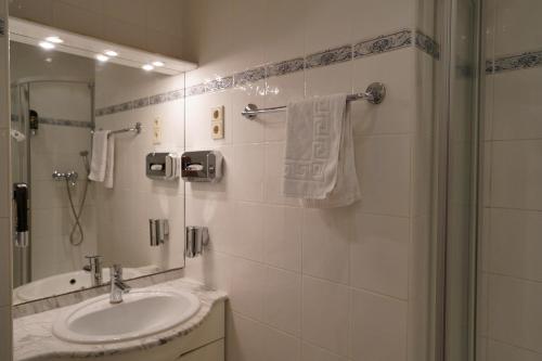 a white bathroom with a sink and a shower at Hotel Xantener Eck in Berlin