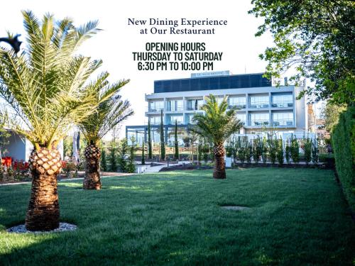a group of palm trees in a yard with a building at Hotel Villa Rosetta in Savudrija